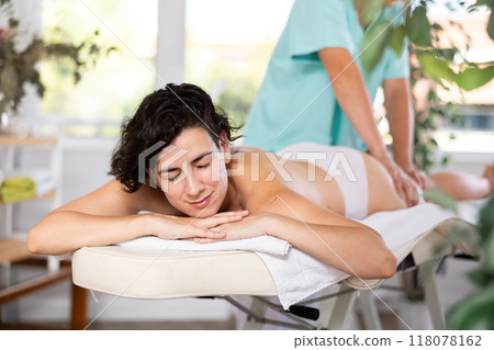 Masseur doing thigh massage to adult woman 118078162