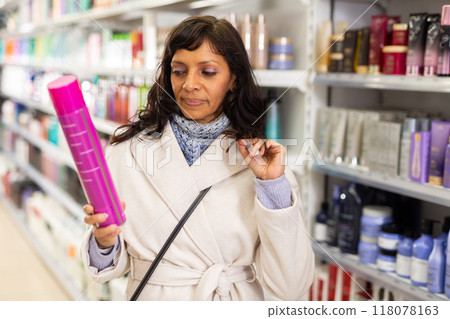 Woman choosing hair shampoo in cosmetics store Woman choosing hair shampoo in cosmetics store 118078163