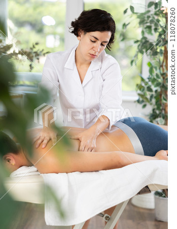 Adult woman giving back massage to young guy 118078260