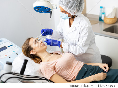 Woman cosmetician giving face injections of botulinum toxin for young woman Woman cosmetician giving face injections of botulinum toxin for young woman 118078395
