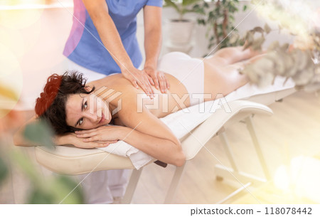 Portrait of woman enjoying relaxing massage by professional masseur Portrait of woman enjoying relaxing massage by professional masseur 118078442