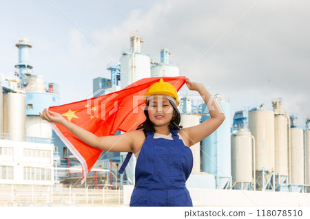Teenage girl in blue overalls waving the flag of China against backdrop of modern metallurgical plant Teenage girl in blue overalls waving the flag of China against backdrop of modern metallurgical plant 118078510
