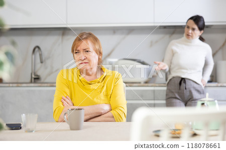 Adult woman and young woman during quarrel in kitchen Adult woman and young woman during quarrel in kitchen 118078661
