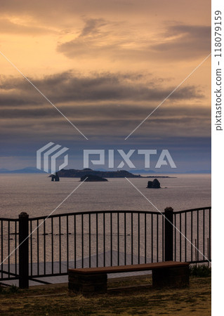 Sunset over the sea and a bench 118079159