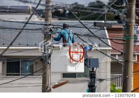 Workers repairing power lines in a residential area 118079243