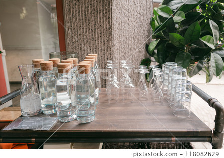 Outdoor table lined with glass bottles and glasses 118082629