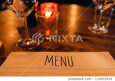Menu and wine glasses on a candlelit restaurant table Menu and wine glasses on a candlelit restaurant table 118082630