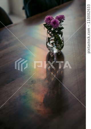 Rainbow-colored lights reflected on a table and purple flowers in a vase Rainbow-colored lights reflected on a table and purple flowers in a vase 118082633