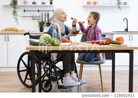 Muslim mother in wheelchair enjoying fresh salad with daughter Muslim mother in wheelchair enjoying fresh salad with daughter 118082911