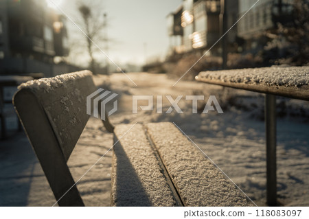 Snow covered bench and winter morning sunshine Snow covered bench and winter morning sunshine 118083097