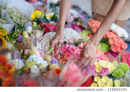 A woman is picking out flowers at a flower market A woman is picking out flowers at a flower market 118083245
