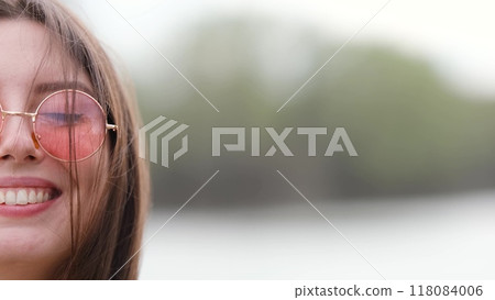 Happy woman in pink sunglasses outdoors smiling Happy woman in pink sunglasses outdoors smiling 118084006