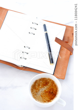 Image of a man working at his desk with a system organizer while drinking a cafe latte, a coffee with plenty of milk Image of a man working at his desk with a system organizer while drinking a cafe latte, a coffee with plenty of milk 118084241