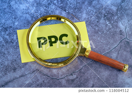 PPC. Pay Per Click concept Businessman working concept, social network, SEO. PPC written through a magnifying glass on a yellow card on an abstract blue background 118084512
