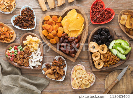 Healthy sweet dried fruits and berries in wooden heart shaped plates on wooden background.Top view. 118085403