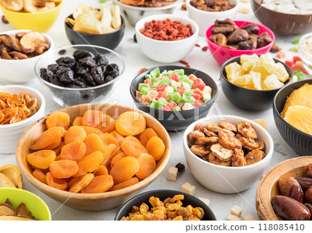 Mix of healthy dried sweet fruits and berries in various bowl plates on light kitchen background. Mix of healthy dried sweet fruits and berries in various bowl plates on light kitchen background. 118085410