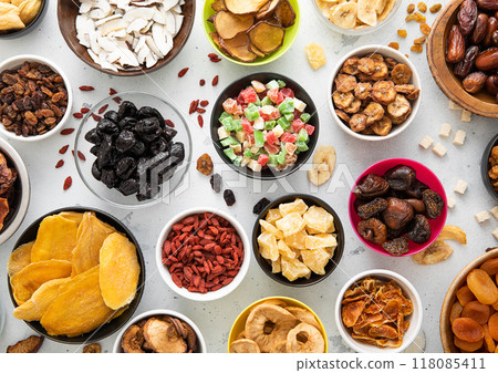 Mix of healthy dried sweet fruits and berries in various bowl plates on light kitchen background. Mix of healthy dried sweet fruits and berries in various bowl plates on light kitchen background. 118085411