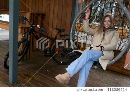 Woman Sitting in Hanging Chair on Porch Woman Sitting in Hanging Chair on Porch 118086314
