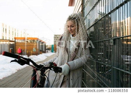Woman Leaning Against Fence Next to Bike Woman Leaning Against Fence Next to Bike 118086358