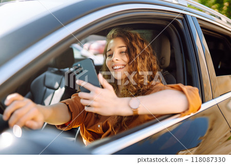 Beautiful woman driver in a car with a phone in her hands. Leisure, travel, technology, navigation. Beautiful woman driver in a car with a phone in her hands. Leisure, travel, technology, navigation. 118087330