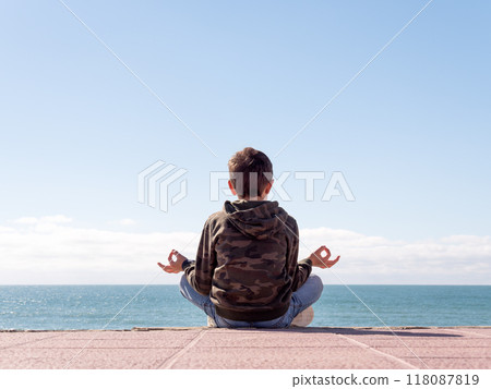 Young Person Meditating by the Sea 118087819