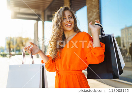 Happy woman with shopping bags walking on sunny street. Concept of lifestyle, buying, selling. 118088155