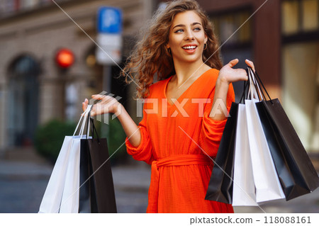 Happy woman with shopping bags walking on sunny street. Concept of lifestyle, buying, selling. Happy woman with shopping bags walking on sunny street. Concept of lifestyle, buying, selling. 118088161
