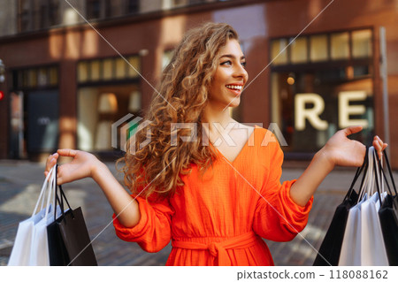 Happy woman with shopping bags walking on sunny street. Concept of lifestyle, buying, selling. Happy woman with shopping bags walking on sunny street. Concept of lifestyle, buying, selling. 118088162