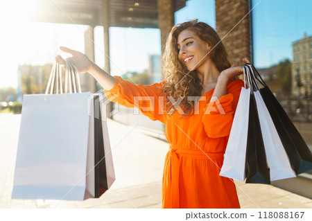 Happy woman with shopping bags walking on sunny street. Concept of lifestyle, buying, selling. 118088167