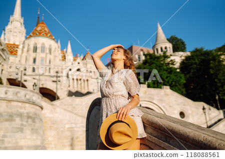 Happy young woman in hat at dawn enjoys view of beautiful buildings. Lifestyle, tourism concept. Happy young woman in hat at dawn enjoys view of beautiful buildings. Lifestyle, tourism concept. 118088561