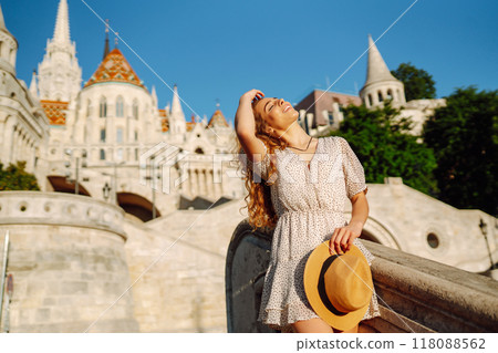 Happy young woman in hat at dawn enjoys view of beautiful buildings. Lifestyle, tourism concept. Happy young woman in hat at dawn enjoys view of beautiful buildings. Lifestyle, tourism concept. 118088562