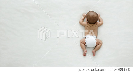 Baby lying on stomach on white blanket raising head 118089358