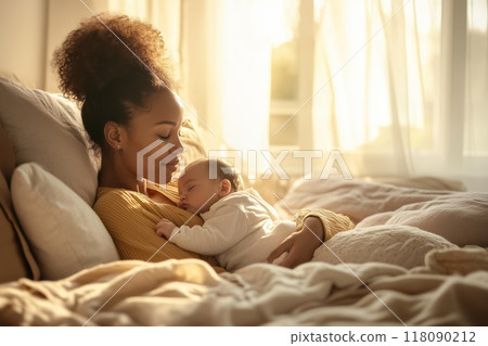 Young mother holding her newborn baby sleeping peacefully in bed 118090212