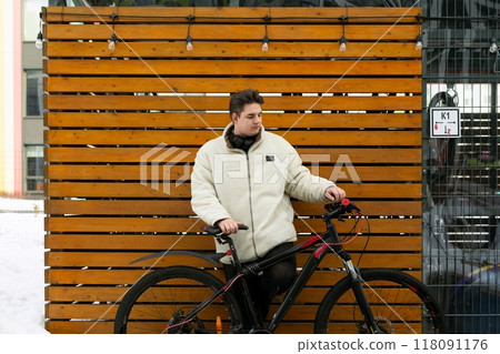 A young European man with a winter jacket took his bike outside A young European man with a winter jacket took his bike outside 118091176