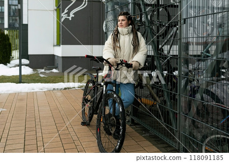 Woman Standing Next to Bike by Fence 118091185