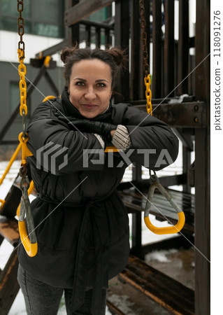 Young pretty woman in a winter jacket walking on the playground Young pretty woman in a winter jacket walking on the playground 118091276