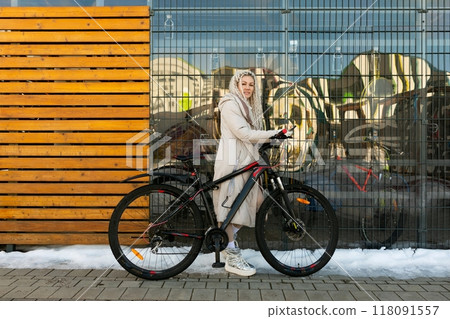Woman Standing Next to Bike in Front of Building 118091557