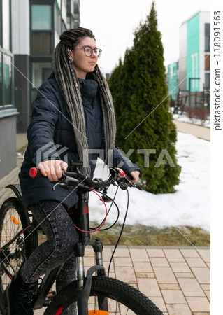 Urban pretty woman with dreadlock hairstyle rides a bicycle 118091563
