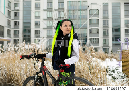 Woman Standing Next to Bike In Front of Tall Building Woman Standing Next to Bike In Front of Tall Building 118091597