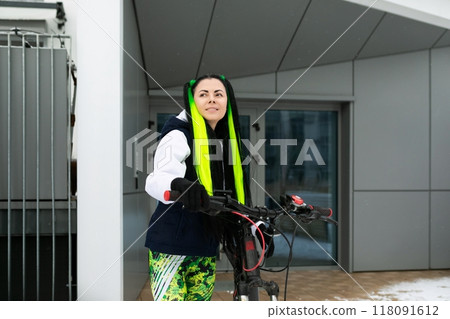 Woman Standing Next to Bike in Front of Building 118091612
