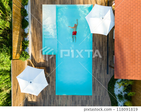 Man swimming alone in the luxury villa swimming pool. Aerial top view. Careless summer vacation concept image 118091819