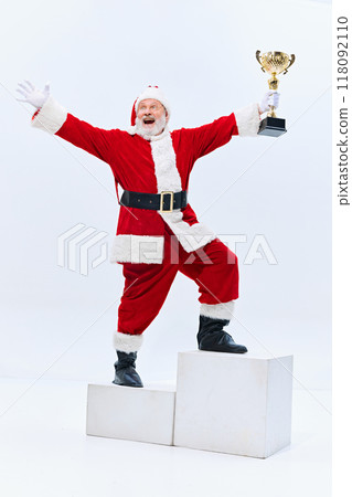 Santa stands on top step of podium, arms wide and trophy raised, exuding excitement as if he's won grand prize against white studio background. Santa stands on top step of podium, arms wide and trophy raised, exuding excitement as if he's won grand prize against white studio background. 118092110