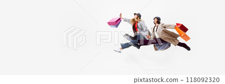 In motion to sales. Young beautiful women in stylish clothes energetically running with many shopping bags. Shopping journey. 118092320
