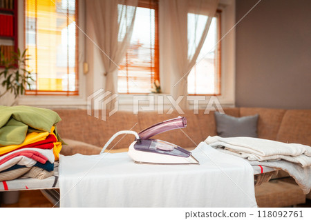 Iron is on t-shirt on ironing board. Concept of household fire danger with electric household appliances. Copy space 118092761