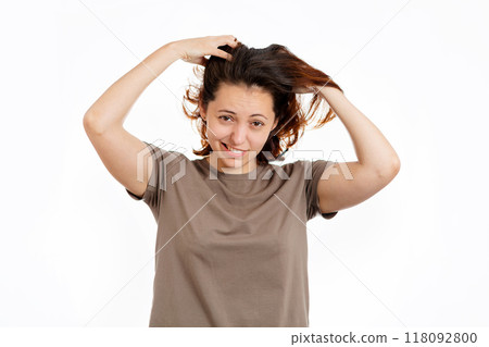 Woman holds her hands to her hair with concern. White background. The concept of hair care Woman holds her hands to her hair with concern. White background. The concept of hair care 118092800