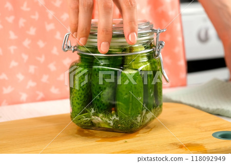 Woman turning around glass jar cooking pickles on kitchen home, hands close-up. Woman turning around glass jar cooking pickles on kitchen home, hands close-up. 118092949
