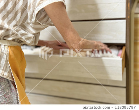 The hands of an elderly woman opening a dresser drawer and searching for something The hands of an elderly woman opening a dresser drawer and searching for something 118093797
