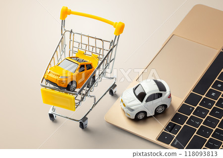 Toy car in shopping cart with laptop on gold table, online selling, buying car, auto insurance Toy car in shopping cart with laptop on gold table, online selling, buying car, auto insurance 118093813