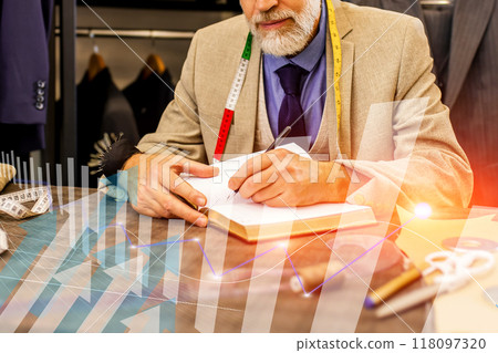 A man is writing in a notebook while looking at a graph A man is writing in a notebook while looking at a graph 118097320