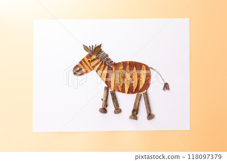 Zebra like animal figure, creatively crafted from natural materials. Yellow and brown stripes , autumn dry leaves craft, foliage, 118097379